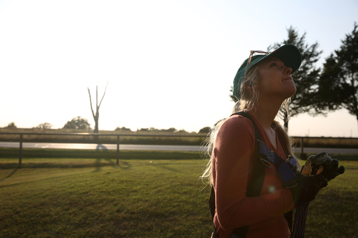 A backlit woman looks up and out of frame, smiling.