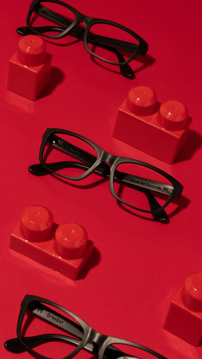 black glasses lying on a red surface with red lego blocks around it