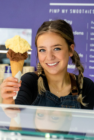 Smiling woman holding two ice cream cones in front of ice cream shop– Melbourne brand photography by Marcie Raw