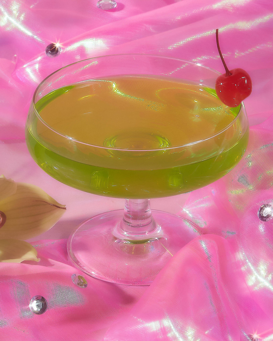 green cocktail on a pink reflective background 