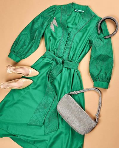 a flatlay of green maxi dress and accessories on a beige background