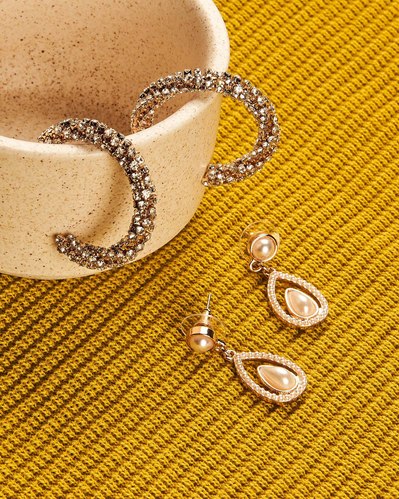 gold earrings lying on a yellow blouse