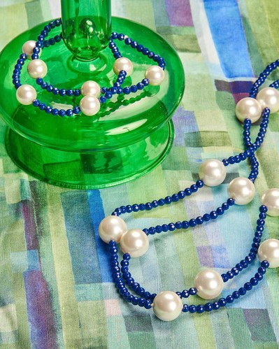 blue necklace and a blue bracelet lying on a green and blue background