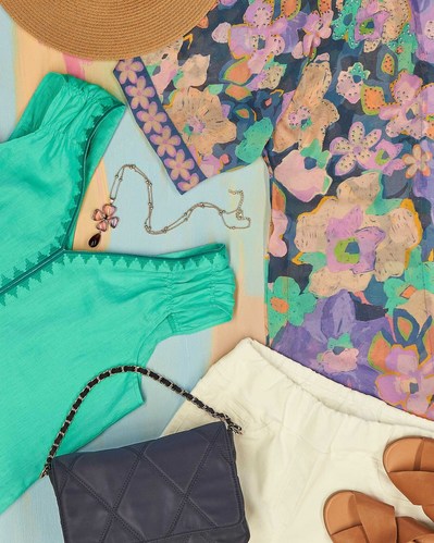 a flatlay of floral blouse, green blouse, white pants
