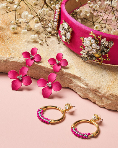 hot pink earrings and hot pink headband lying on a stone surface