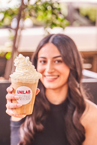 a young beautiful girl showing iced coffee and looking at the camera 