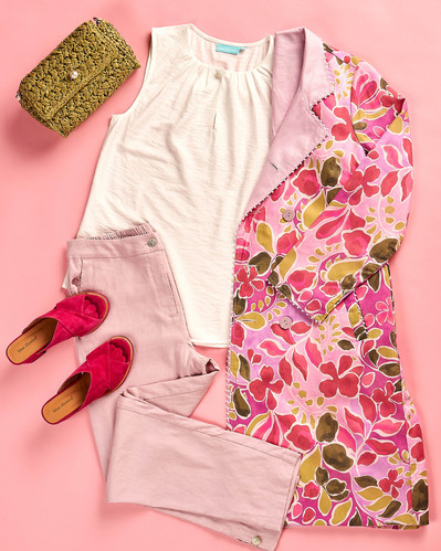 a flatlay of white t shirt, floral coat and pink trousers on a pink background