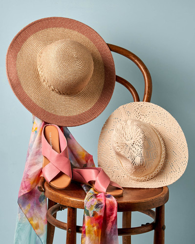 summer hats and baby pink shoes lying on a wooden chair