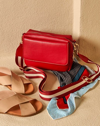 red bag and tan flat shoes sitting on a shelf
