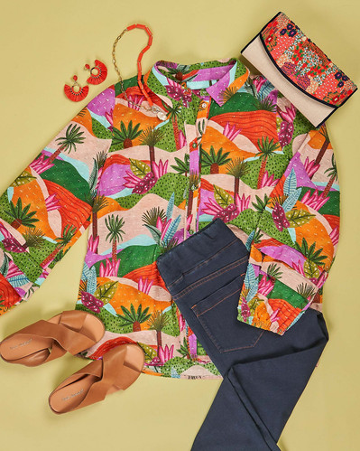 a flatlay of colourful blouse, jeans and tan shoes lying on a green background