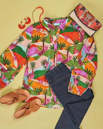 a flatlay of colourful blouse, jeans and tan shoes lying on a green background