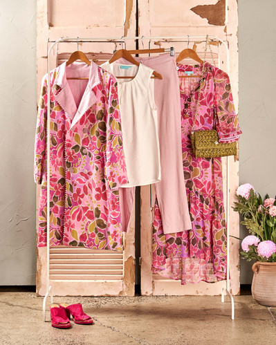 a floral coat, floral dress, white blouse sitting on a white rack