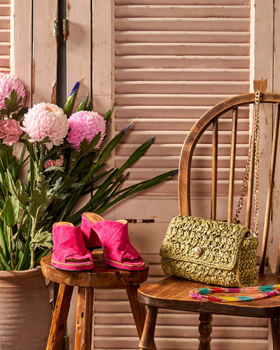 green bag and pink shoes sitting on a wooden chair
