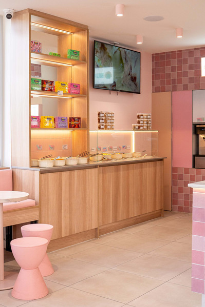 a pink interior of a frozen yoghurt place with machines for yoghurt making in the background