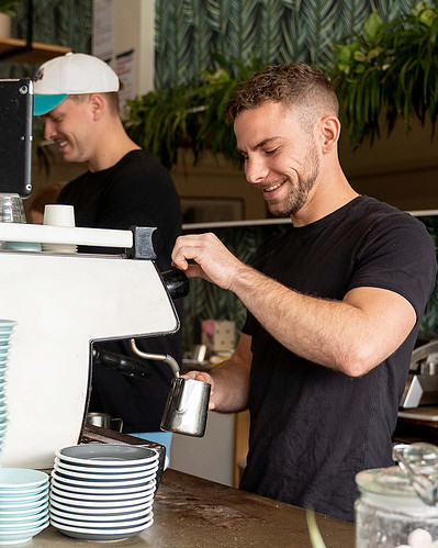 Barista steaming milk at café espresso machine – coffee lifestyle photography by Marcie Raw, Melbourne