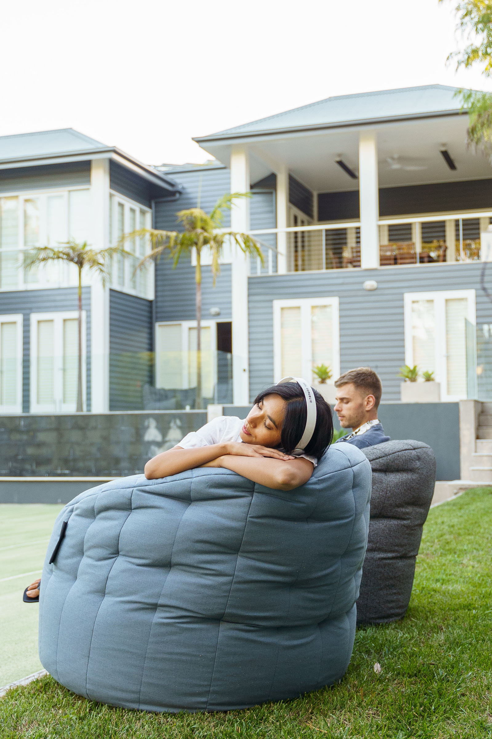a girl relaxing on a big bean bag outside 