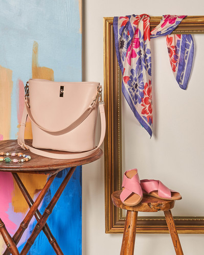a bag sitting on a wooden table next to pink shoes sitting on a small stool