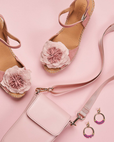 baby pink shoes and baby pink bag lying on a pink backdrop