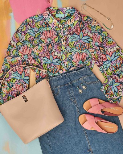 a flatlay of floral blouse and jeans skirt and accessories 