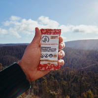 Hand holding an energy bar with forest and mountains in background — outdoor product photography Melbourne