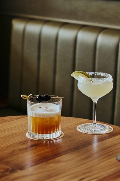 two cocktails sitting at the table in a wine bar