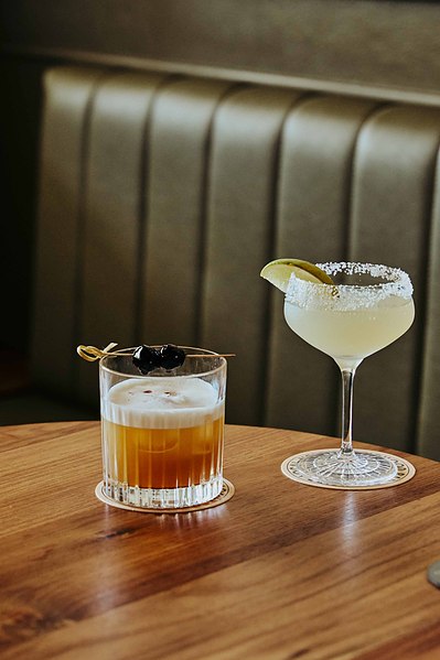 two cocktails sitting at the table in a wine bar