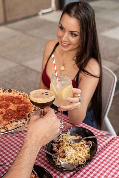 a beautiful girl cheering her peril spritz with a boy at the restaurant table