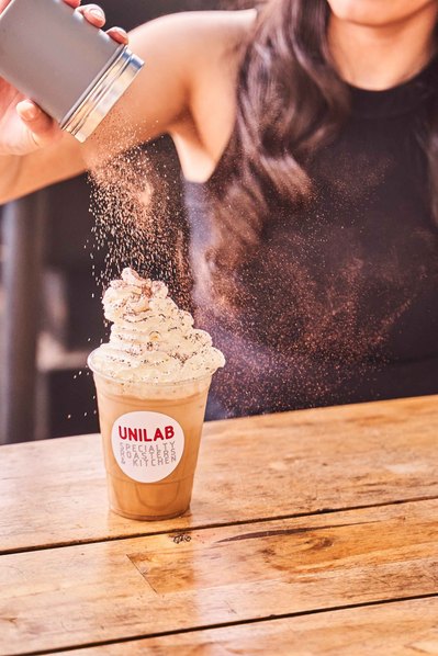 a girl putting chocolate powder on iced coffee