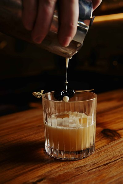 a close up shot of a cocktail being poured and droplets dropping in a glass