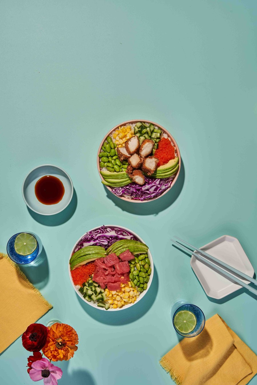 two poke bowls with soy sauce and water in glasses on a blue background