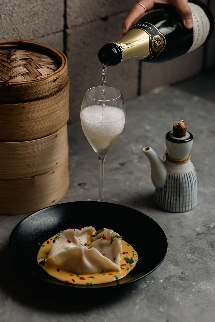 dumplings on a plate and a hand pouring champagne onto a glass