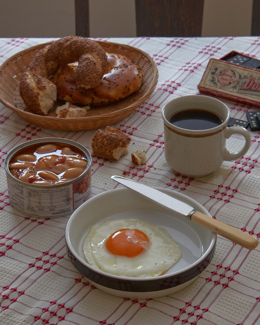 breakfast on a table with an egg on a plate, black coffee, bagels