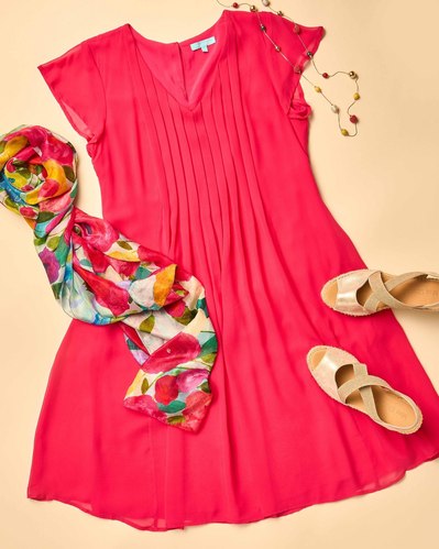 a flatlay of red dress, tan espadrilles and a colourful scarf on a beige background