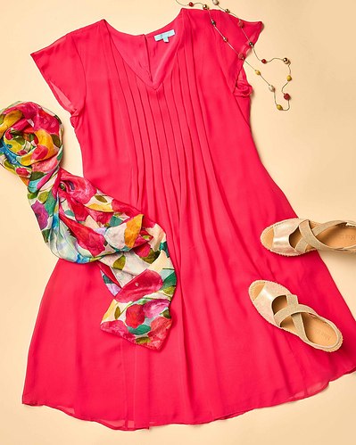 a flatlay of red dress, tan espadrilles and a colourful scarf on a beige background