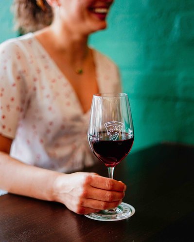 a girl smiling and holding a glass of red wine in a restaurant 