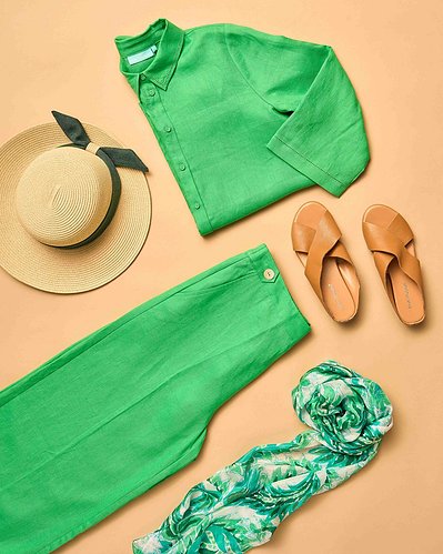a flatlay of green shirt and green pants and tan espadrilles  on a beige background