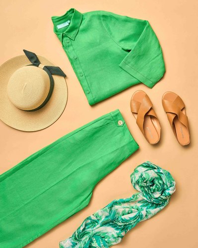 a flatlay of green shirt and green pants and tan espadrilles  on a beige background