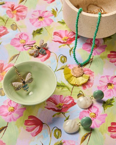 a butterfly earrings and a long green and yellow necklace on a flower background