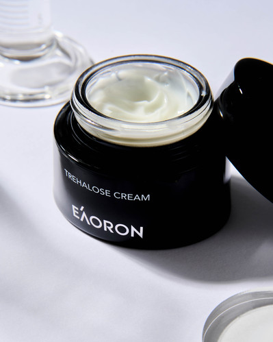 a face cream in a black packaging lying on a white background with shadows