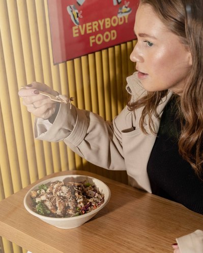 a girl eating a salad at a restaurant window