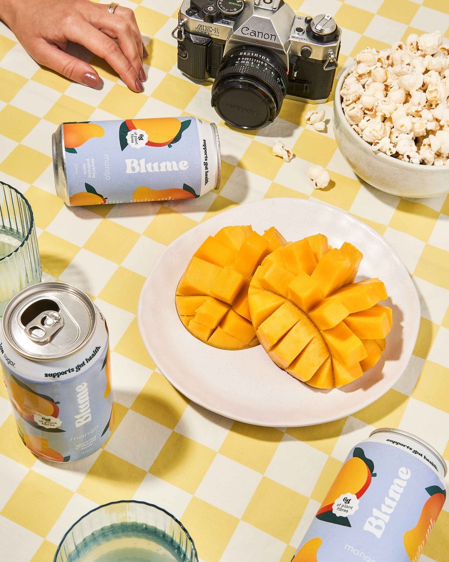 cut mango on a plate, a camera and popcorn on a table