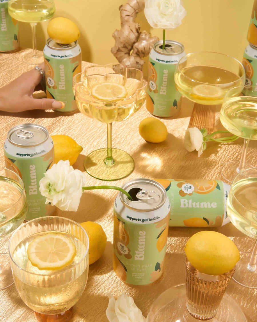 a spread with kombucha cans, fresh lemons and flowers on a table 