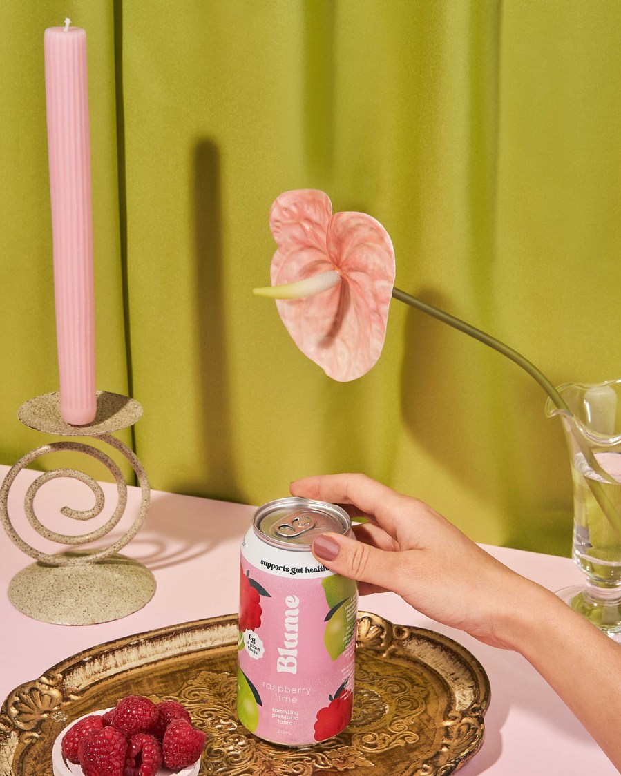 a hand holding a pink kombucha 