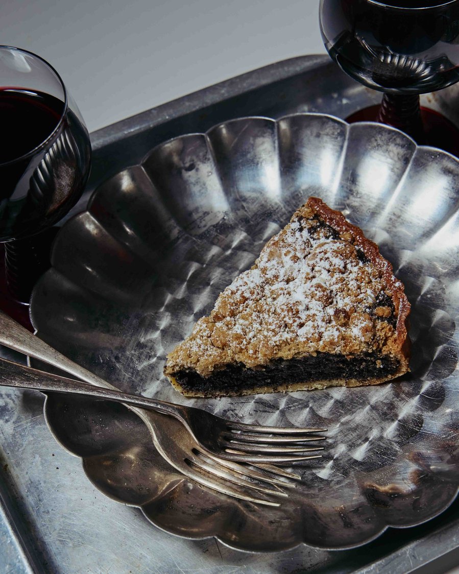 a piece of apple pie on a plate with wine next to it