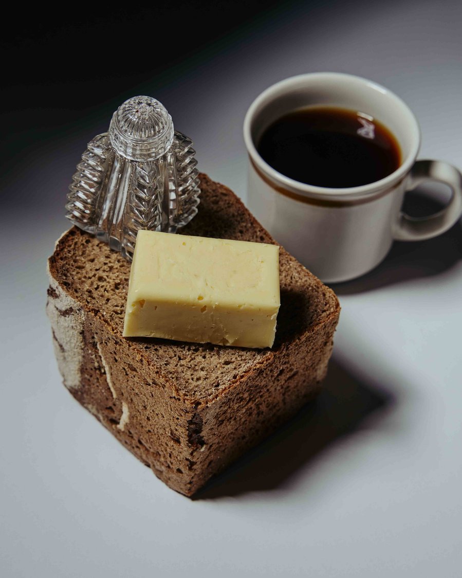 half a loaf of bread with black coffee and salt shaker next to it