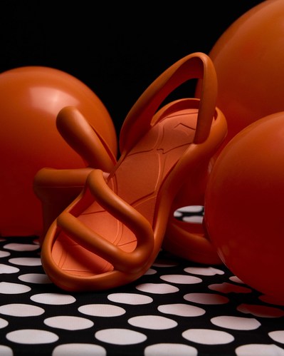 orange camper shoe on a polka dot background surrounded by orange balloons