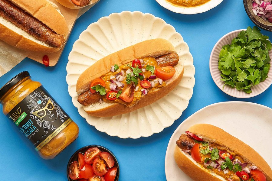 hot dogs with fresh ingredients next to them such as coriander, tomatoes, onions