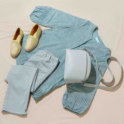 a flatlay of blue blouse and blue pants and accessories 