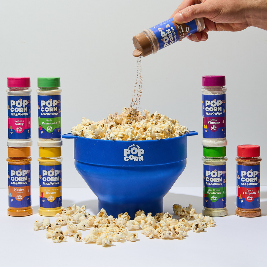 a hand pouring a popcorn flavouring onto a bowl with popcorn
