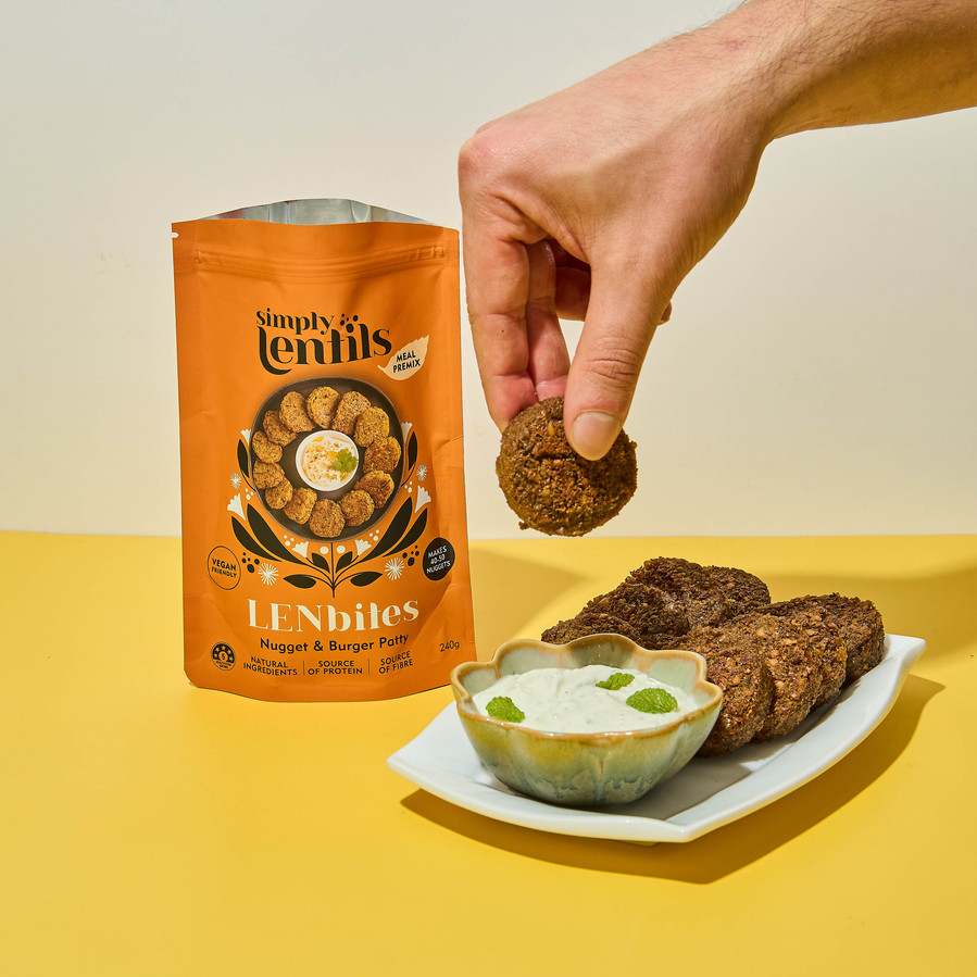 a hand dipping a falafel in tzatziki sauce